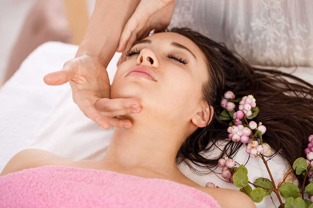 Relaxing facial massage with berries and flowers surrounding a peaceful woman.