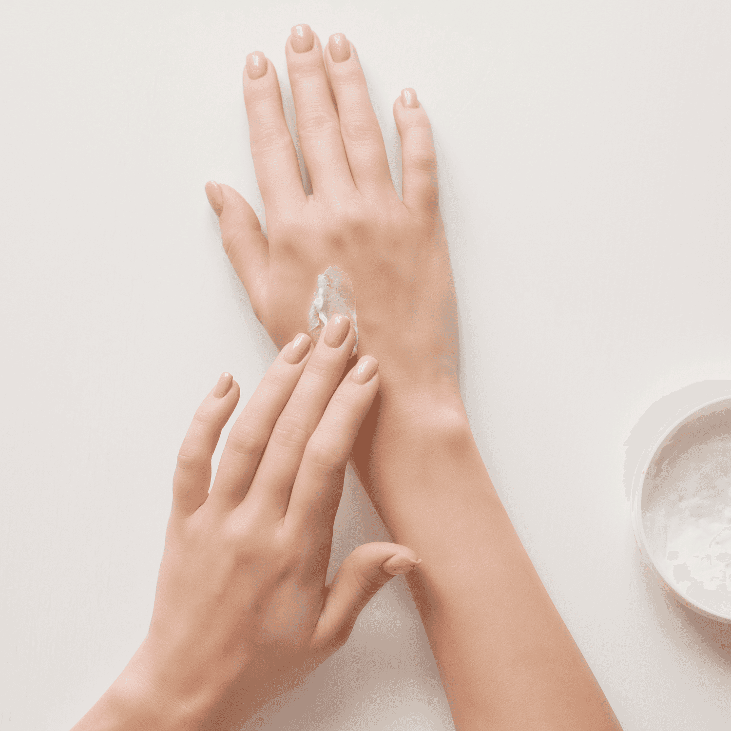 Applying moisturizer to hands on a white background.